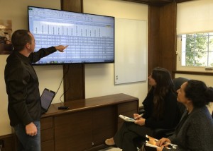 PHOTO CAPTION: Justin Wilkins, Operations Manager (standing) reviews data from PHP’s new Strategic Plan with other PHP staff, Erica Valdes, Associate Development Director (center) and Arcelia Sencion, Director of Health Care and Social Services (right).